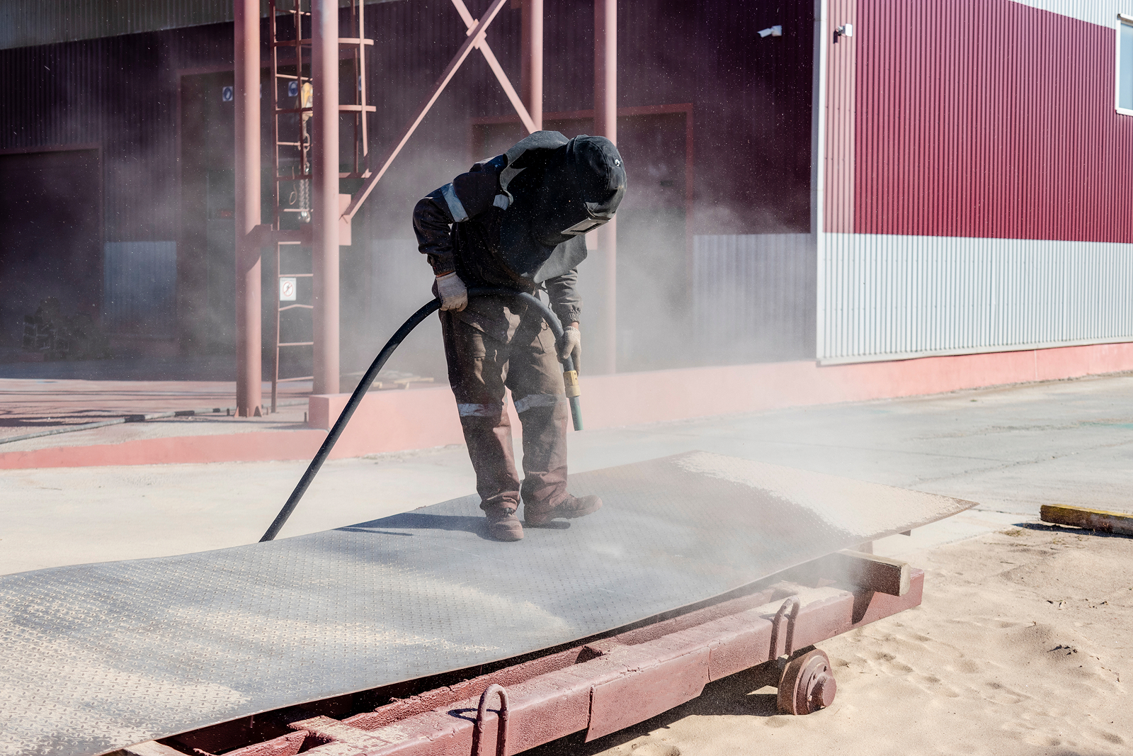 Worker sandblasting steel to bare metal